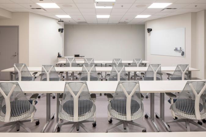 Image of 291 seminar room in Clark Hall with white chairs facing presenter podium